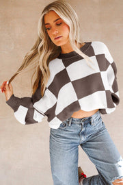 Model wears brown and white checkered knit sweater with bishop sleeves and cropped hem