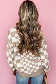 Person wearing beige and white checkered drop shoulder sweater from behind against pink wall