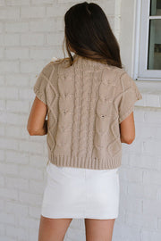 Taupe cable knit sweater showing round neck and relaxed shift silhouette