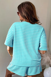 Person wearing turquoise and white striped loose tee and matching shorts from behind in a room