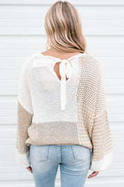 Relaxed knit keyhole sweater showing mixed-pattern texture and long wide sleeves