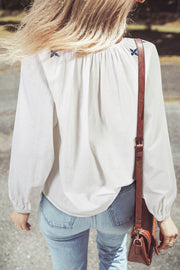 Embroidered white blouse showing round neckline with button detailing