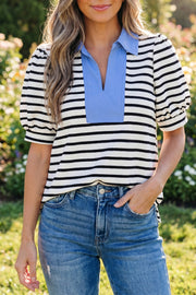 Woman wearing black and white striped short puff sleeve blouse with blue color block polo collar, standing outdoors in jeans