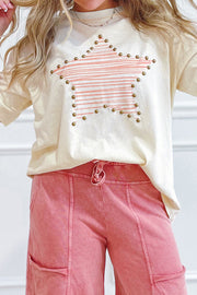 Person wearing beige cotton jersey top with star print and gold studs, paired with pink pants