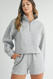 Close view of the zip front and stand collar on light grey sweatshirt