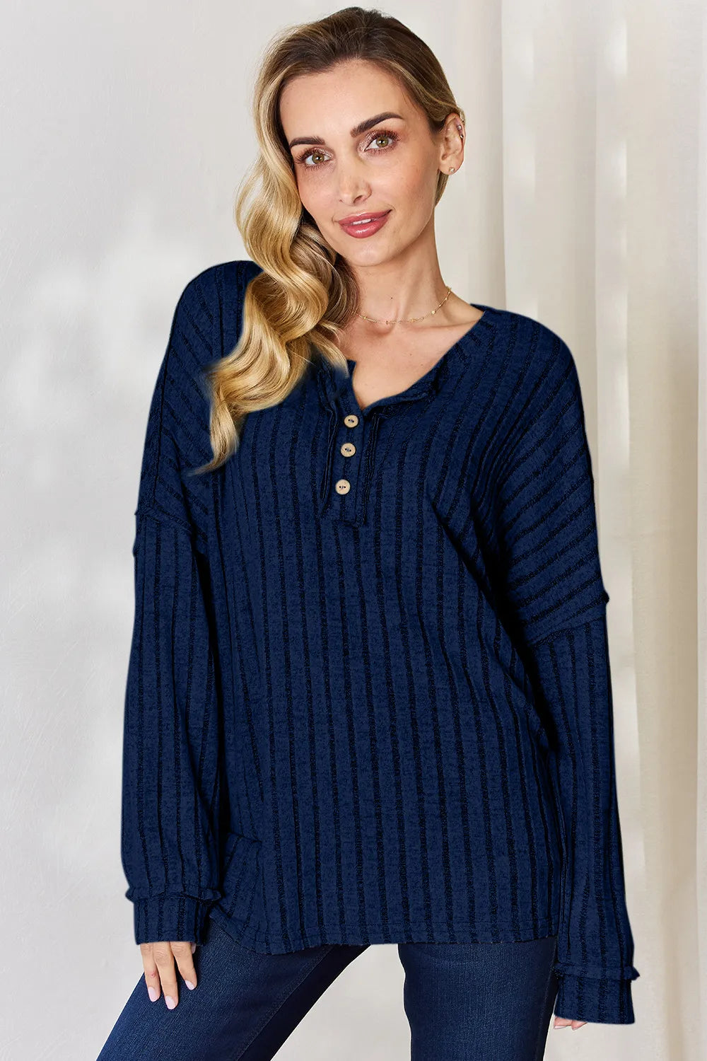 A woman wearing a navy blue ribbed half button long sleeve t-shirt