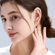 Crown-style claw-set moissanite huggie earrings catching the light