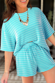 Model wearing turquoise and white striped loose tee and matching drawstring shorts, smiling outdoors