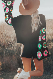 Loose crochet sweater showing bell sleeves with floral detail