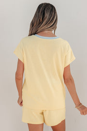 Back view of a person wearing a pale yellow ribbed short set with light blue trim at neckline