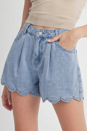 Light blue denim shorts with scalloped hem, shown on a person from the waist down