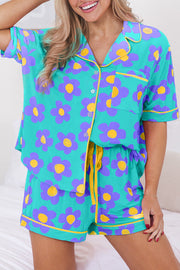 Person wearing teal short sleeve pajama set with purple and yellow floral print, sitting on bed