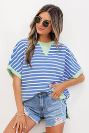 Woman wearing sky blue and white striped loose short sleeve top with light green contrast trim, paired with denim shorts