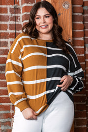 Plus size colorblock striped patchwork loose top in mustard and black, worn by a woman against a brick wall