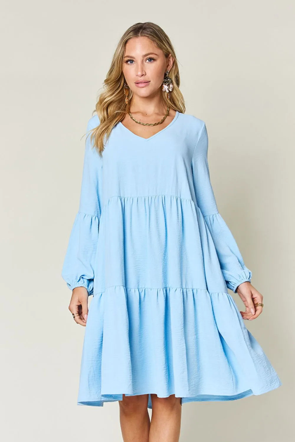 Light blue V-neck dress with balloon sleeves and tiered skirt, shown on model
